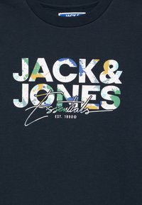 T-shirt girocollo blu navy con grafica audace e multicolore "JACK & JONES" e dettagli a macchie di vernice, con "Essentials" scritto in corsivo sotto.