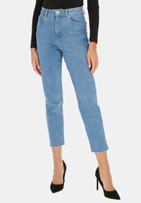 Jasnoniebieskie, wysokie dżinsy z dopasowanym krojem, skróconą długością, postrzępionym dołem i klasycznym pięci pocketsowym wzorem. W połączeniu z czarnymi szpilkami.