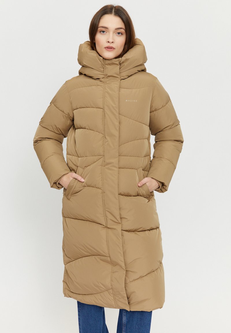 Long, brown puffer coat with a high collar, large hood, and quilted design. Features two front pockets and subtle branding on the chest.