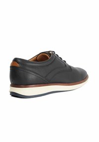 Black leather shoe with a textured finish, rounded toe, and contrasting brown accents. Features a white and navy rubber sole.