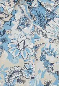 Bloemenschirt met lichtblauw, marineblauw en crème kleuren. Beschikt over een knoopsluiting met grote bloemenpatronen en een zachte katoenen textuur.