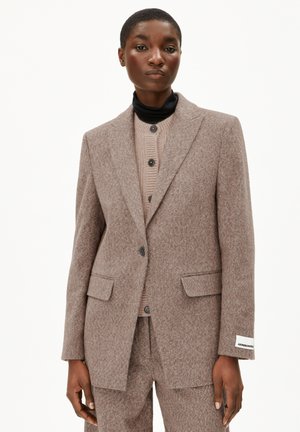 Blazer marron texturé avec deux poches avant et une fermeture à bouton unique, superposé sur un top beige en tricot côtelé, avec un col noir.