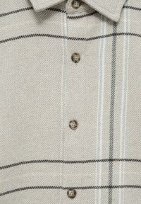 Beige geruite blouse met een textuurweefsel, bruin knopen en dunne zwarte en groene strepen. Gekraagd ontwerp met een verticale knopenrij.