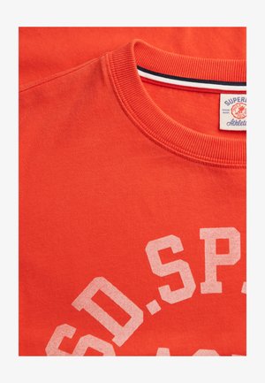 Red cotton T-shirt with a crew neckline, featuring a white graphic text print and subtle ribbed texture on the collar.