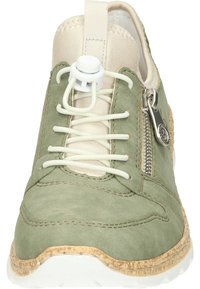Baskets en suède vert avec des détails crème, lacets élastiques, zip latéral et une semelle en liège texturée. Bout arrondi avec des accents de couture visibles.