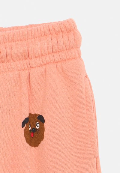 Ροζ πλεκτό παντελόνι με ελαστική μέση και μικρό κεντημένο καφέ πρόσωπο σκύλου με μαύρα αυτιά και κόκκινη γλώσσα μπροστά.