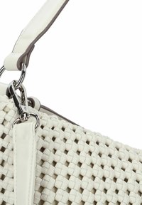 Sac à main tissé beige avec une surface texturée, présentant une bandoulière en cuir blanc et des accents en métal argenté. Design compact et structuré.