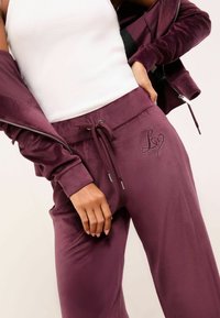 Samt-Loungewear-Set in tiefem Burgund. Elastischer Bund mit Kordelzug. Auffälliges "L♥" Stickdetail. Enganliegendes weißes Tanktop.