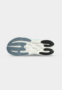 Semelle de chaussure avec une surface texturée présentant des parties en caoutchouc bleu, blanc et noir ainsi que des rainures pour l'adhérence sur un fond clair uni.