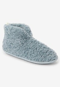 Zapatilla azul acogedora, hecha de material texturizado y suave. Diseño de altura hasta el tobillo con un forro interior suave y suela flexible.