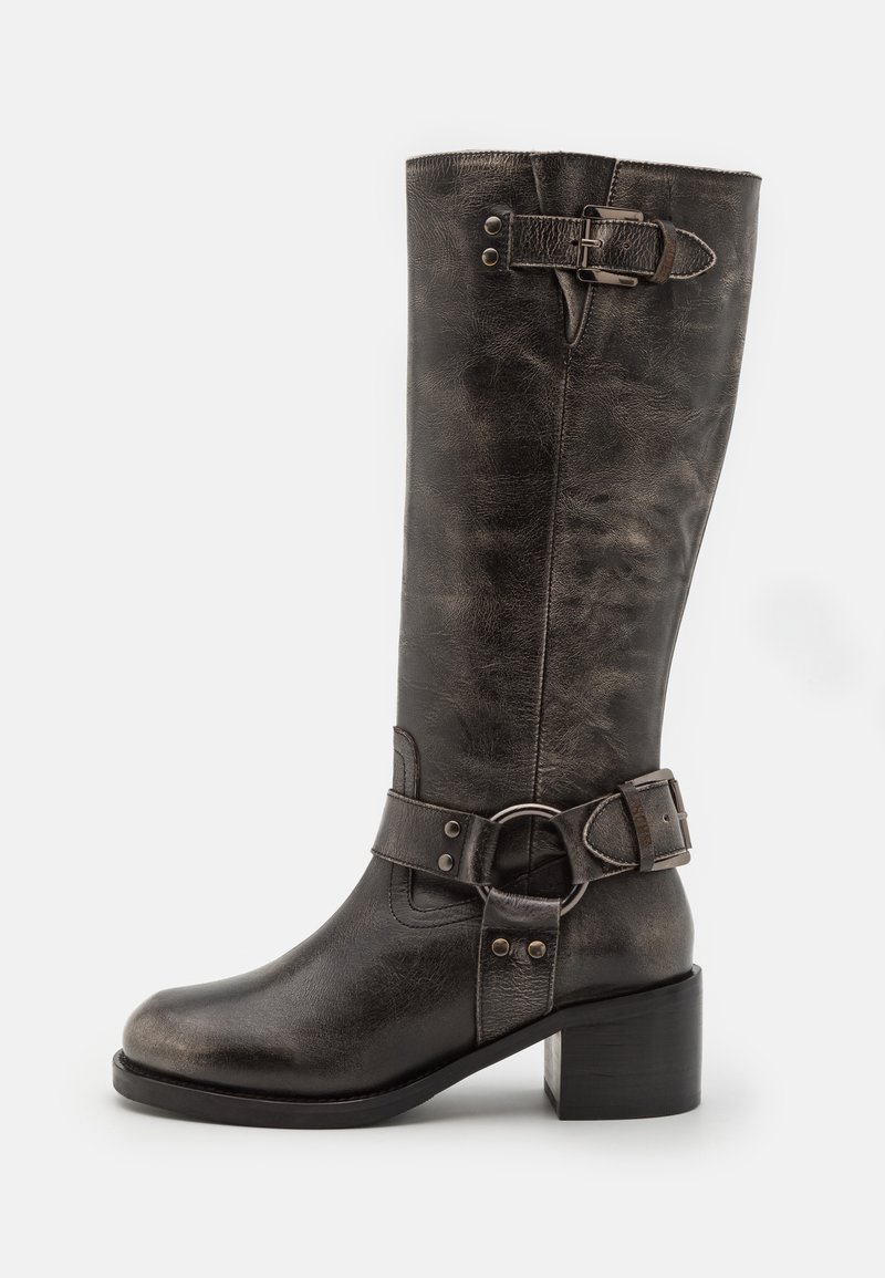 Botte en cuir noir jusqu'au genou avec un large talon bloc, arborant une boucle et une sangle à la cheville ainsi qu'une finition texturée.