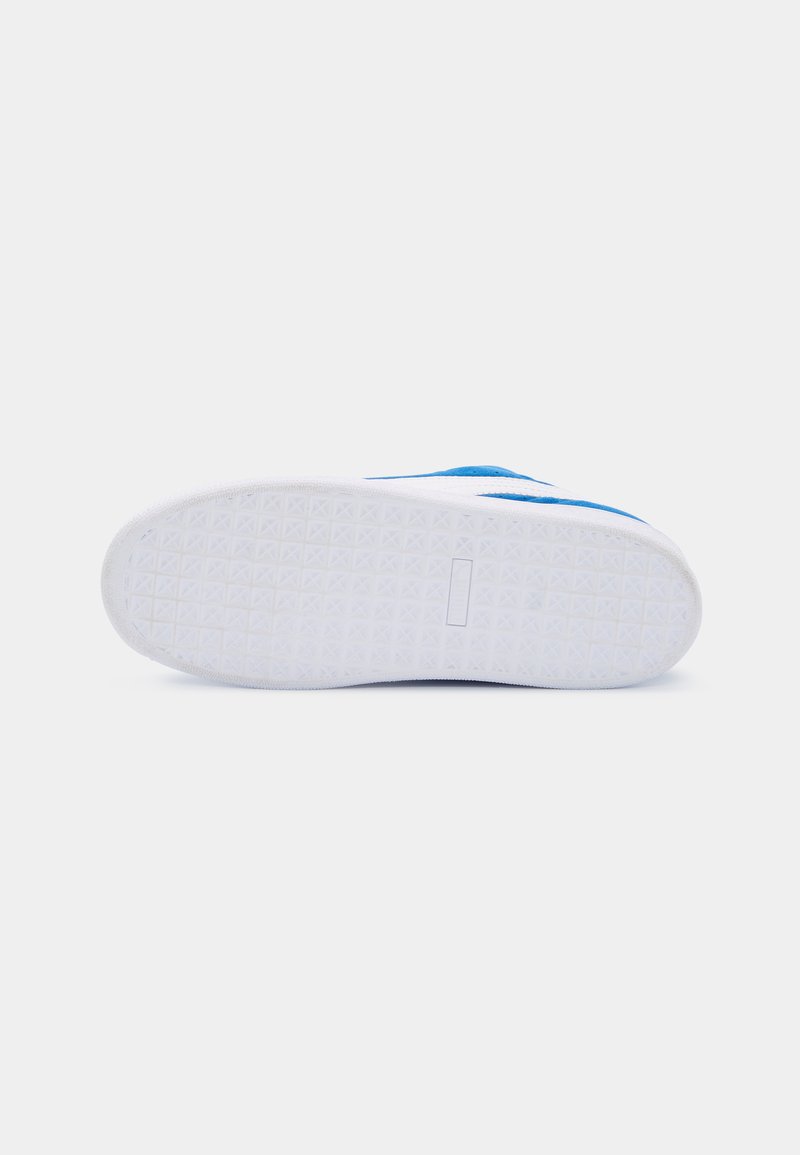 Baskets bleues avec une semelle en caoutchouc blanc texturé et un design plat. La tige est en tissu lisse avec de subtils accents bleus.