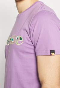 Fialové bavlněné tričko s vyšitým textem "prosím" v několika barvách, krátkými rukávy a logem na levém rukávu.