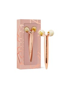 Różowo-złoty roller do twarzy z kremowymi końcówkami, umieszczony w różowej pudełku o wzorze geometrycznym. Posiada branding na uchwycie.
