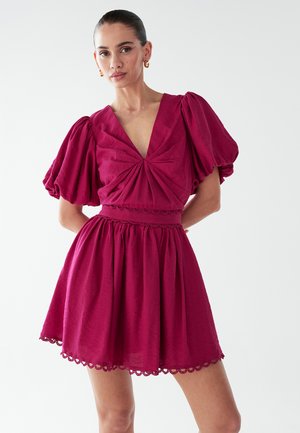 Vestido fucsia con mangas abullonadas, escote en V y cuerpo fruncido. Falda acampanada con borde de volantes en el dobladillo. Hecho de una tela liviana.
