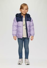 Giacca imbottita viola e blu navy con cappuccio, dotata di zip frontale e polsini elasticizzati. Indossata sopra una maglietta leggera e jeans di denim.