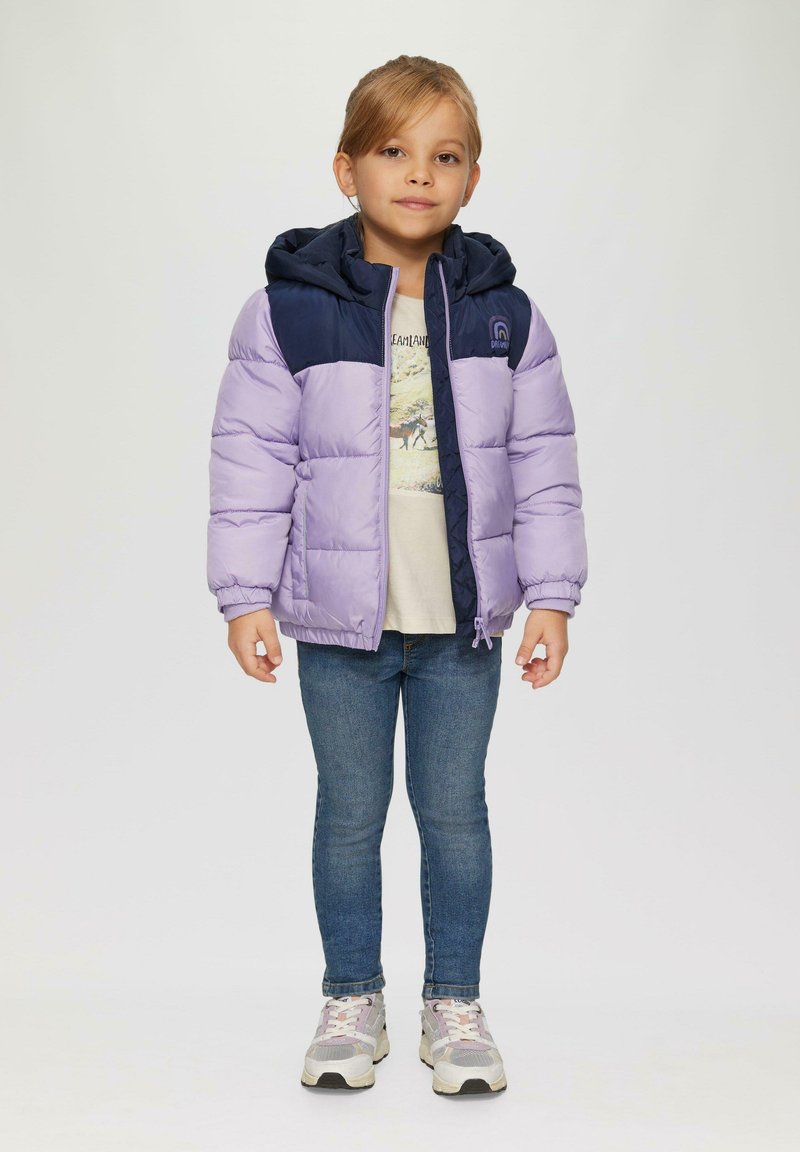 Giacca imbottita viola e blu navy con cappuccio, dotata di zip frontale e polsini elasticizzati. Indossata sopra una maglietta leggera e jeans di denim.