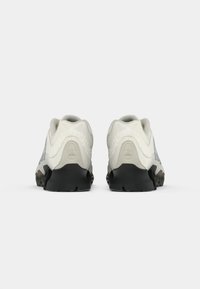 Pair of white and light gray Adidas sneakers with black soles, viewed from the back on a plain white background.