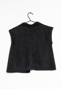 Svart ärmlös väst i ett mjukt, texturerat tyg. Har en rundad krage och en rak fåll, hängande från en svart krok.