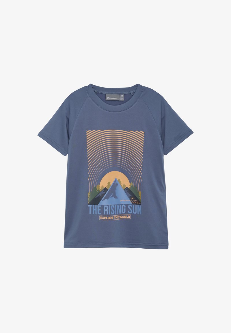 Camiseta de manga corta azul con un estampado gráfico de montañas y un sol, con el texto "EL SOL NACIENTE" y "EXPLORA EL MUNDO."