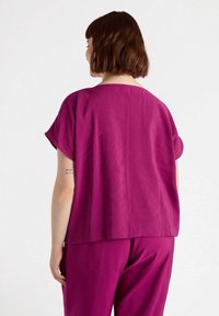 Top fucsia casual con maniche corte, dotato di scollatura tonda e orlo dritto, realizzato in un tessuto leggero e testurizzato.