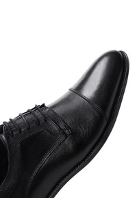 Chaussure de ville en cuir noir avec un bout pointu, des panneaux texturés et un laçage. Fini lisse avec des détails de couture et une semelle élégante.