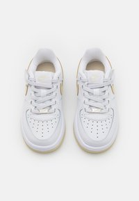 Weiße Leder sneakers mit einem perforierten Zehenbereich und flachen Schnürsenkeln. Merkmale ein goldenes Swoosh-Logo und eine strukturierte Gummisohle.