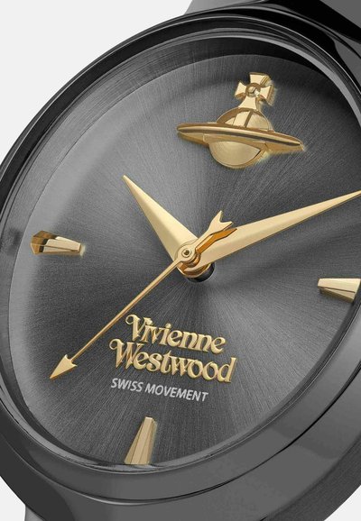 Montre-bracelet noire avec un cadran gris rond et texturé. Index et aiguilles dorés, avec une icône Saturne dorée au-dessus du nom de la marque. Mouvement suisse.