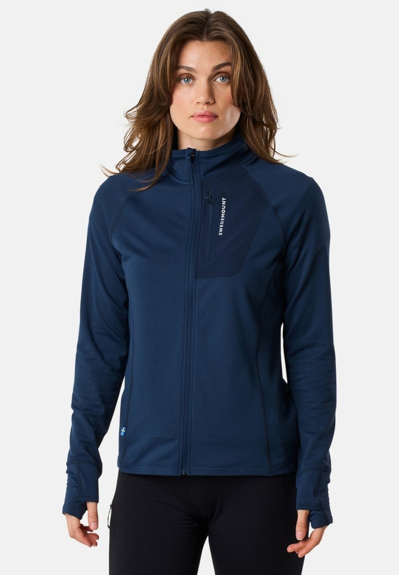 Marinblå zip-up jacka i lättviktsmaterial med en åtsittande design, lång ärm och tumhål. Inkluderar en liten ficka med dragkedja.