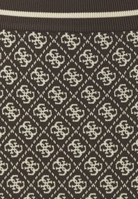 Tissu tricoté avec un fond marron et un motif crème répété de formes florales stylisées dans des contours en losange.
