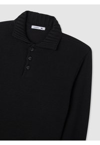 Polo shirt in maglia nera con colletto a coste, patta con tre bottoni e tessuto testurizzato. L'etichetta riporta "Terranova XL."