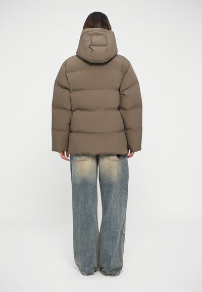 Brown puffer jacket with a hood, featuring a quilted design. Worn over light blue distressed wide-leg jeans. Smooth, soft texture.