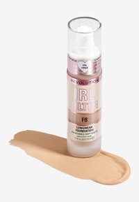 Fond de teint longue tenue Revolution IRL Filter en F8, sans huile, dans un flacon pompe transparent. Échantillon de couleur beige moyen sur fond blanc.