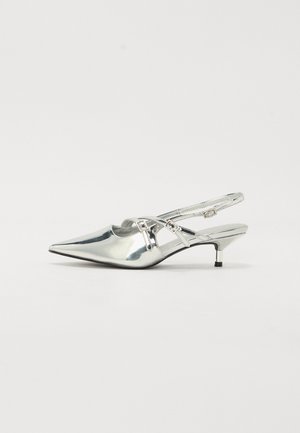 Błyszczący srebrny but typu slingback z ostrym noskiem, niskim obcasem typu kitten i cienkimi podwójnymi paskami krzyżującymi się na górze z małymi klamrami.