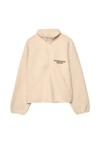 Pullover i cremefarvet nuance lavet af blødt stof, med kvart-lynlås, sidelommer og broderet tekst "Portobello Sundays LONDON."