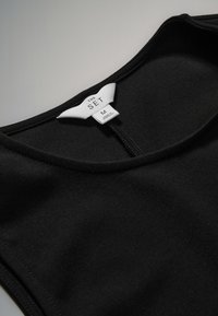 Black sleeveless top with round neckline and sewn-in white label reading "THE SET M Made in Morocco."