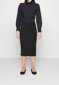 Chemise noire à manches longues avec devant boutonné et col, associée à une jupe crayon noire à côtes et des chaussures plates noires. Style simple et ajusté.