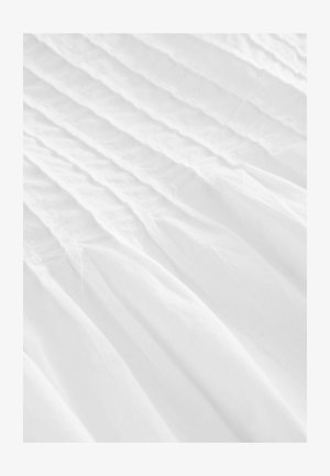 Biała tkanina z pionowymi plisami, charakteryzująca się gładką fakturą i przezroczystym wyglądem, tworząca miękkie, płynące linie na całej powierzchni.