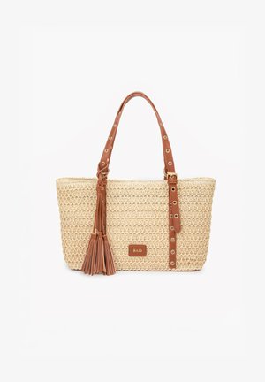 Bolso tote beige tejido con asas de cuero marrón, detalles con ojales, adornos con borlas y una pequeña etiqueta "RAID" en la parte delantera.