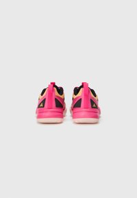 Rosa sneakers til sport med sorte og gule accenter, der har en struktureret overdel, solid hæl og varemærker på bagsiden.