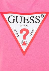 Lyserød bomulds-T-shirt med et hvidt, rødkantet trekantet logo med "GUESS U.S.A." og et centralt rødt spørgsmålstegn.