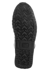 Sole in gomma nera con un motivo a rilievo profondo, caratterizzato da forme a zigzag e esagonali. Include un logo prominente sul lato.
