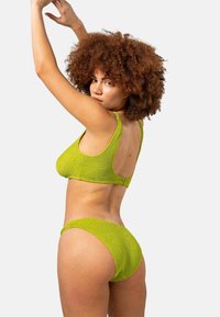 Groene geribbelde bikini set met een mouwloze top met een lage rug en bijpassende hipster onderkant, beide gemaakt van textuurstof.