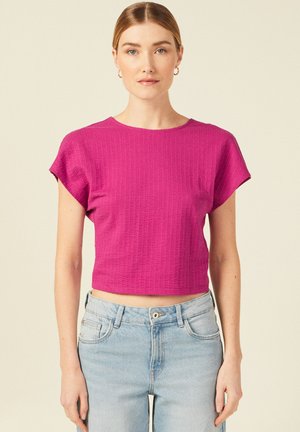 Top fucsia corto in tessuto texture con maniche corte, scollatura tonda e un motivo sottile, abbinato a jeans light blue a vita alta.