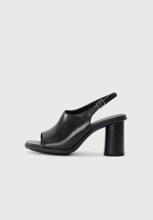 Black leather open-toe slingback heeled sandal with a rounded silhouette and a thick cylindrical heel. Features an adjustable ankle strap.