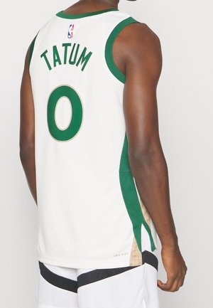 Camiseta de baloncesto blanca con ribetes verdes, con "TATUM" y el número "0" en verde y dorado, con detalle DRI-FIT en el dobladillo.