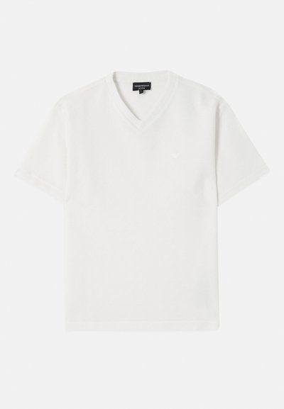 Camiseta blanca de manga corta con cuello en V, confeccionada en una tela texturizada con un patrón sutil. Presenta un pequeño logo en el pecho.