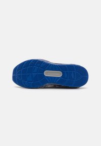Puma footwear outsole in blue rubber with textured tread pattern and a central logo in grey, featuring a sturdy, curved shape.