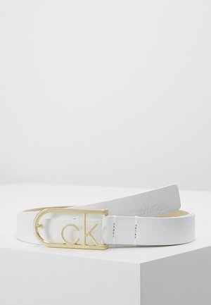 White leather belt with a gold Calvin Klein "ck" logo buckle, displayed coiled on a white surface with embossed branding on the strap.