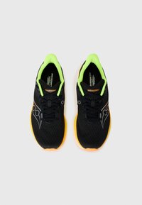 Zapatillas deportivas negras con parte superior de malla, acentos en verde neón y suelas naranjas. Presentan cordones y un logo en el lateral.